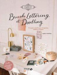 Couverture du livre "Brush Lettering et Doodling" montrant un bureau lumineux décoré de créations en calligraphie moderne.