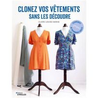 ouverture du livre 'Clonez vos vêtements sans les découdre' de Sophie Denys posée sur une table de travail en bois, entourée d'outils de couture : une chemise en lin, des ciseaux dorés, un mètre ruban et du papier à patron.