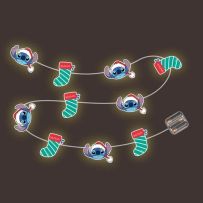 Vue de la guirlande Stitch en fonctionnement dans l'obscurité. Chaque motif (tête de Stitch et chaussette rayée) est rétroéclairé par une LED, créant une aura lumineuse jaune et chaleureuse autour des personnages.