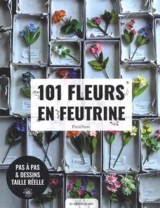 Couverture du livre "101 fleurs en feutrine" de PieniSieni publié aux Éditions de Saxe. Le visuel original met en scène une multitude de délicates fleurs colorées en feutrine, minutieusement disposées dans de petites boîtes rectangulaires à la manière d'u