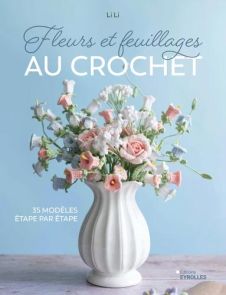 Couverture du livre Fleurs et feuillages au crochet avec bouquet de fleurs crochetées délicates dans un vase blanc sur fond bleu pastel, ambiance douce et élégante. Achat sur Divertistore.com.