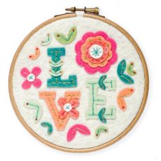 Création terminée du Kit feutrine tambour fleuri Love. Le mot "Love" est entouré de fleurs en feutrine rose, turquoise et corail sur un fond blanc, encadré dans un tambour en bois.