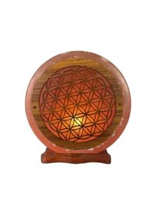 Photographie d'une lampe en cristal de sel rose de l'Himalaya de forme circulaire, posée sur un socle en bois foncé. La face avant de la lampe est ornée d'une plaque ronde en bois incrustée et délicatement ajourée, représentant le motif géométrique sacré 